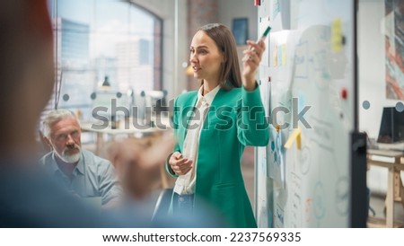 Female CEO Using Whiteboard in Office to Answer Questions and Give Feedback to her Team During a Meeting. Portrait of Beautiful Woman Doing Presentation in Creative Agency