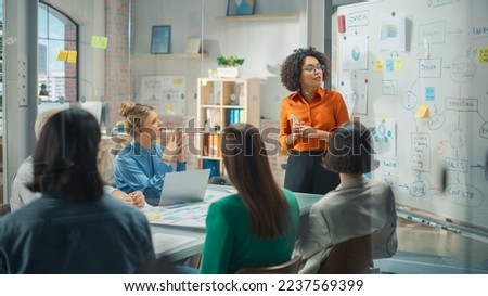 Beautiful Black Businesswoman Gives Report, Presentation to Her Business Colleagues in the Conference Room, She Shows Graphics, Pie Charts and Company's Growth on a Whiteboard