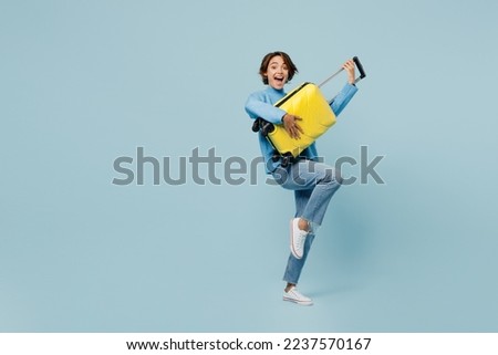 Full body traveler woman wear sweater hold suitcase pov guitar isolated on plain pastel light blue cyan color background. Tourist travel abroad in free spare time rest getaway Air flight trip concept Royalty-Free Stock Photo #2237570167