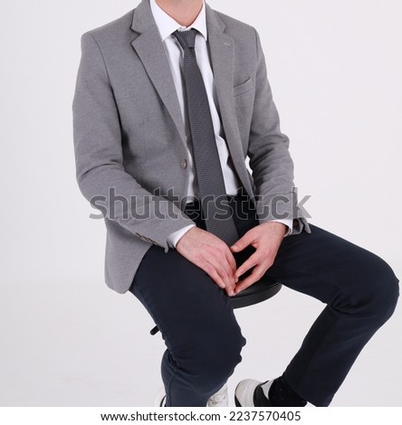 A man is sitting on a chair in business clothes. Photo session on a white background in a business theme.