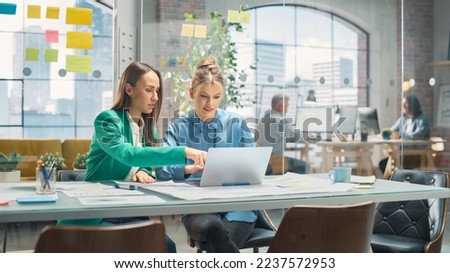 Portrait of Two Creative Colleagues Collaborating and Pointing at the Laptop in Modern Office. Female Manager Consults White Project Manager, They Brainstorm on the Project. Royalty-Free Stock Photo #2237572953