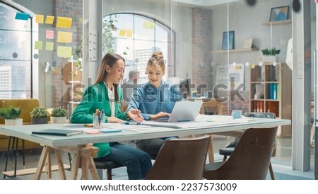 Two Colleagues Working On Laptop in Office. Female Help Desk Coordinator Collaborates with Caucasian Customer Service Agent, They Discuss a Project, Chat, Smile. Teamwork Collaboration Royalty-Free Stock Photo #2237573009
