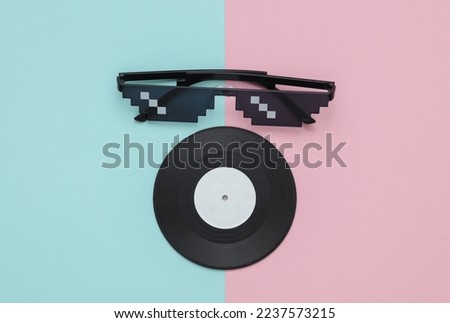 Stereo headphones with vinyl record on blue pastel background. Music concept