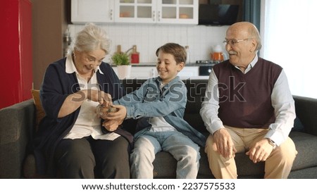 Little boy visiting his grandfather. Little boy eating colorful candies with his grandparents. Portrait of visiting the elderly.