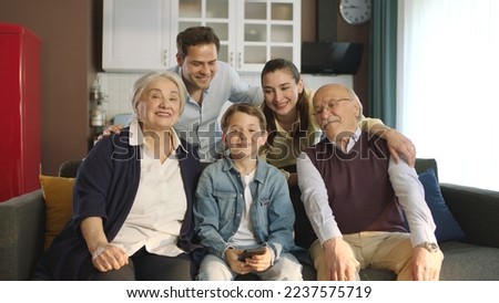 Young couple with children, their son and elderly parents sitting on sofa in living room, taking self portraits together. Portrait of happy cheerful big family smiling at camera in cozy living room. Royalty-Free Stock Photo #2237575719