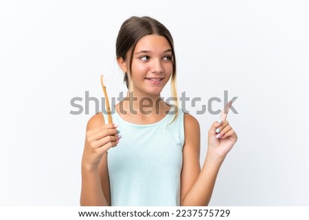 Little caucasian girl holding a toothbrush isolated on white background intending to realizes the solution while lifting a finger up