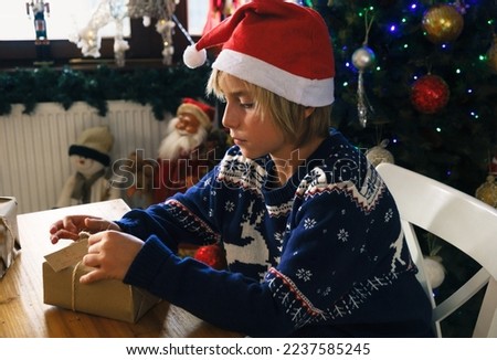 Cute boy with a Santa Claus hat making Christmas handcraft presents
