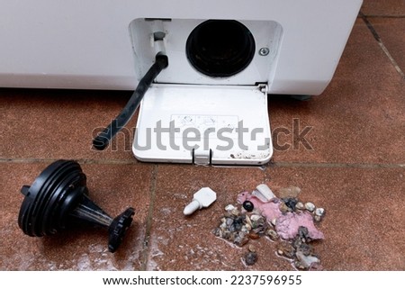 Washing machine clog removal. Garbage removed from the filter of a horizontal loading washing machine Royalty-Free Stock Photo #2237596955