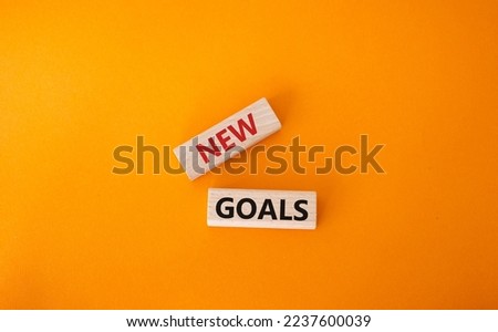 New goals symbol. Wooden blocks with words New goals. Beautiful orange background. Business and New goals concept. Copy space.