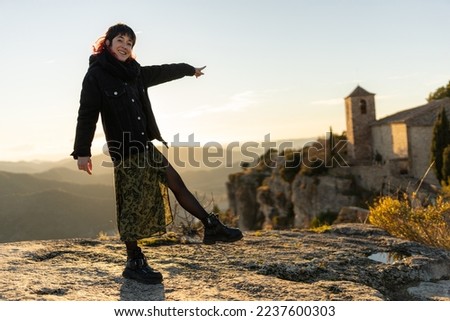 red haired woman walking on rocks at sunset with a village in the background