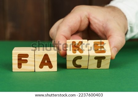 Business concept. On a green surface, a man puts cubes with the inscription - FAKE, FACT Royalty-Free Stock Photo #2237600403