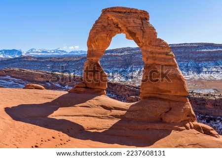 Winter Delicate Arch - A closeup view of Delicate Arch, with snow-covered La Sal Mountains towering in background, on a clear sunny Winter day. Arches National Park, Utah, USA.  Royalty-Free Stock Photo #2237608131