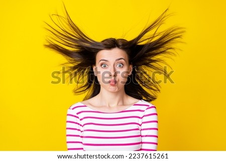 Photo portrait of charming young woman inflate cheeks flying hair foolish wear stylish striped clothes isolated on yellow color background