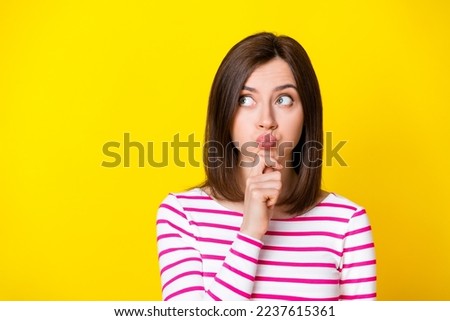 Photo of gorgeous young woman thoughtful look empty space hold air fooling dressed trendy striped look isolated on yellow color background