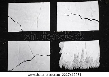 Four torn sheets of white paper on a black wall. Royalty-Free Stock Photo #2237617281
