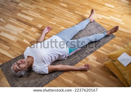 Woman lying on yoga mat after workout. Fit female relaxing on floor at home. Royalty-Free Stock Photo #2237620167