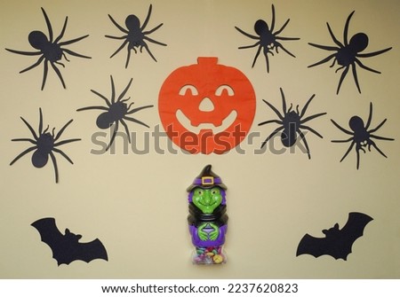 Scary Halloween figurines stand on a light background in close-up, behind hangs terrible pumpkin. Cute character in monster costume. Halloween concept. Holiday decorations toys