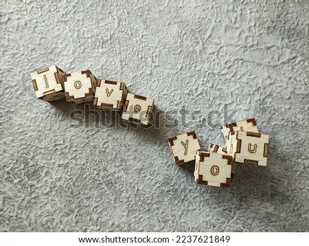 Wooden cubes with text "LOVE YOU" on gray textured background. Selective focus image
