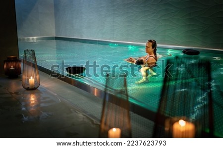 Therapeutic exercise in the pool. Woman receiving an aquatic therapy in the pool. Water relaxation and deep meditation.