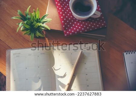 Agenda, planner book, calendar, pencil, and cup of coffee place on office desk. Diary for organizer to plan timetable, daily appointment, and management job at room. Planner book Calendar Concept.
