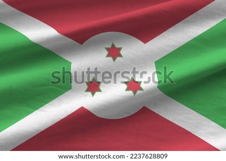 Burundi flag with big folds waving close up under the studio light indoors. The official symbols and colors in fabric banner