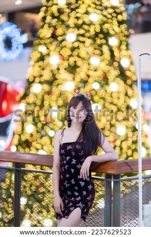 Portrait beautiful young asian woman red dress costume and Christmas greeting picture parcel decoration on Christmas tree light circular bokeh background Decoration During Christmas and New Year.