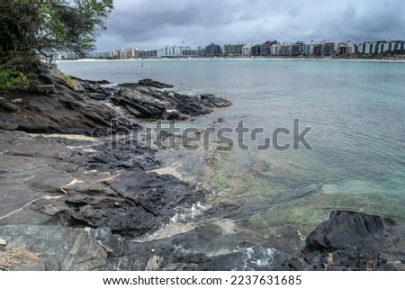The beaches around Fort São Mateus with the city of Cabo Frio in the background, many rocks with sea water around them.
