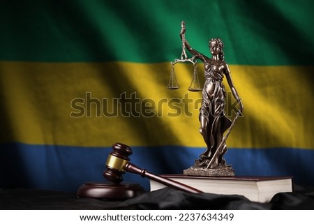Gabon flag with statue of lady justice, constitution and judge hammer on black drapery. Concept of judgement and punishment Royalty-Free Stock Photo #2237634349