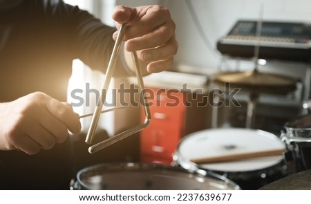 Man hand playing on music triangle beating with metal stick. Musician with traditional instrument in recording studio Royalty-Free Stock Photo #2237639677