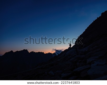Silhouette of a mountaineer tourist with a headlamp on a ridge during colorful sunset, fearless determination courage, Tatra mountains Slovakia Vysoke Tatry Royalty-Free Stock Photo #2237641803