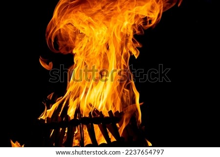 Pile of firewood burning with orange flames on a black background. Burning bonfire in the darkness Royalty-Free Stock Photo #2237654797