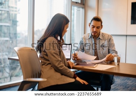 Hispanic male candidate analyzing business documents while having meeting with human resource manager during job interview in the office. Royalty-Free Stock Photo #2237655689