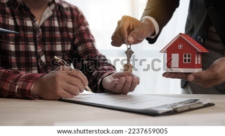 Give a house key, Credit approver, businessman in male suit and house toy model mockup Home loan mortgage approval concept. After signing the contract