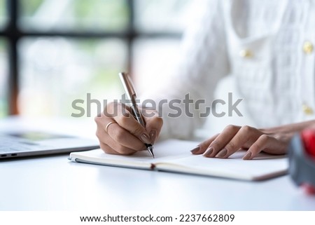 Cropped shot of Asian woman hand using laptop and writing making list taking notes in notepad working or learning on laptop  educational course or training, education online concept