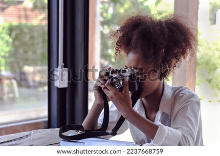 Black hipster tourist woman using camera taking picture in coffeeshop during summer vacation