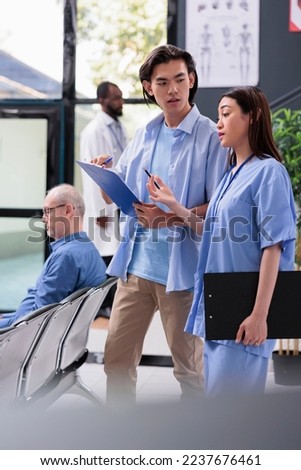 Physician nurse explaining medical expertise to asian patient after showing where need to sign before start consultation during checkup visit in hospital waiting area. Health care service and concept