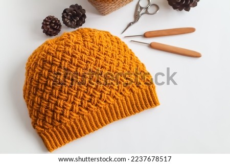 Crochet work with cotton yarn, yarn balls and crochet needles on threshing basket. Handmade and crochet hat. Slouch or beanie hat.