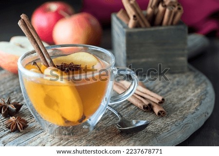 A tea cup filled with hot apple cider with all the ingredients in behind. Royalty-Free Stock Photo #2237678771