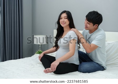 husband massaging shoulders of his pregnant wife on a bed. she suffering from back pain Royalty-Free Stock Photo #2237681585