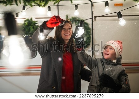 Caucasian woman and son decorate camper for christmas. Happy family travels in a mobile home.