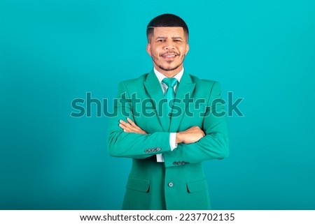 Brazilian black man, dressed in suit and green tie, Businessman. with arms crossed, looking at camera.