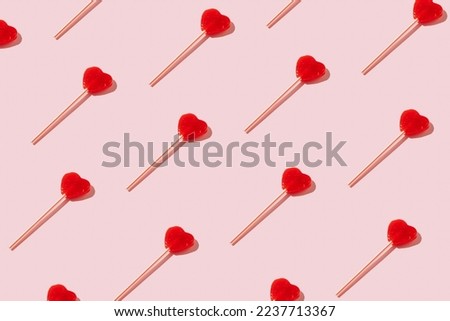 Red heart shaped lollipops pattern on pastel background. Minimal Valentine or love concept. Royalty-Free Stock Photo #2237713367