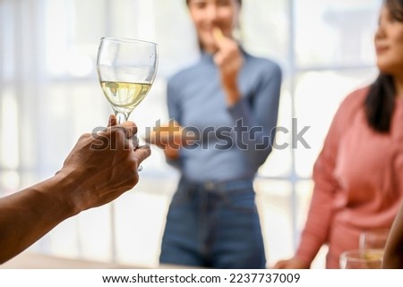 selective focus image, A male hand holding a glass of wine over blurred background of his friends enjoy in the party.