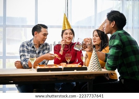 Group of happy and joyful Asian friends enjoy talking while drinking beer and eating pizza together in the party.