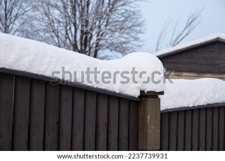 A thick layer of snow has fallen on the edge of the fence. Royalty-Free Stock Photo #2237739931