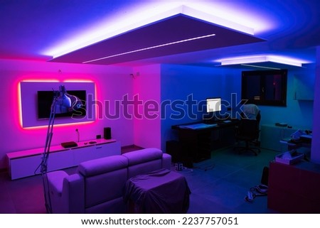 Moving to a new house. House interior. Ideas for basement living room. Entertainment room with TV and color led strips. Royalty-Free Stock Photo #2237757051