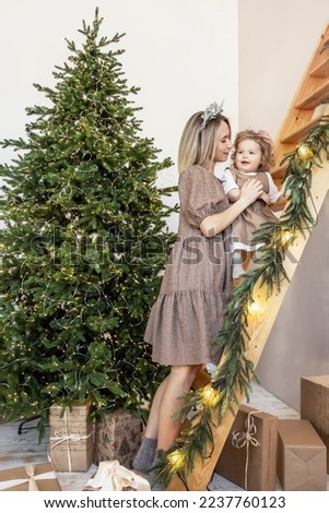 A young woman with blond hair and a little daughter against the backdrop of Christmas decorations. New year concept.