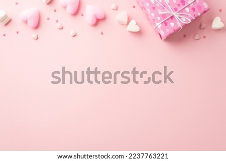 Valentine's Day concept. Top view photo of present box in wrapping paper with heart pattern marshmallow candles and sprinkles on isolated light pink background with copyspace