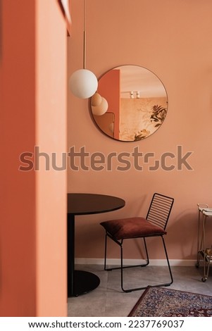 Aesthetic elegant home living room interior with coral walls, comfortable chair, mirror, table, carpet, mirror. Scandinavian interior design