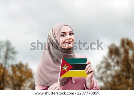 Muslim woman in hijab holds flag of Mozambique